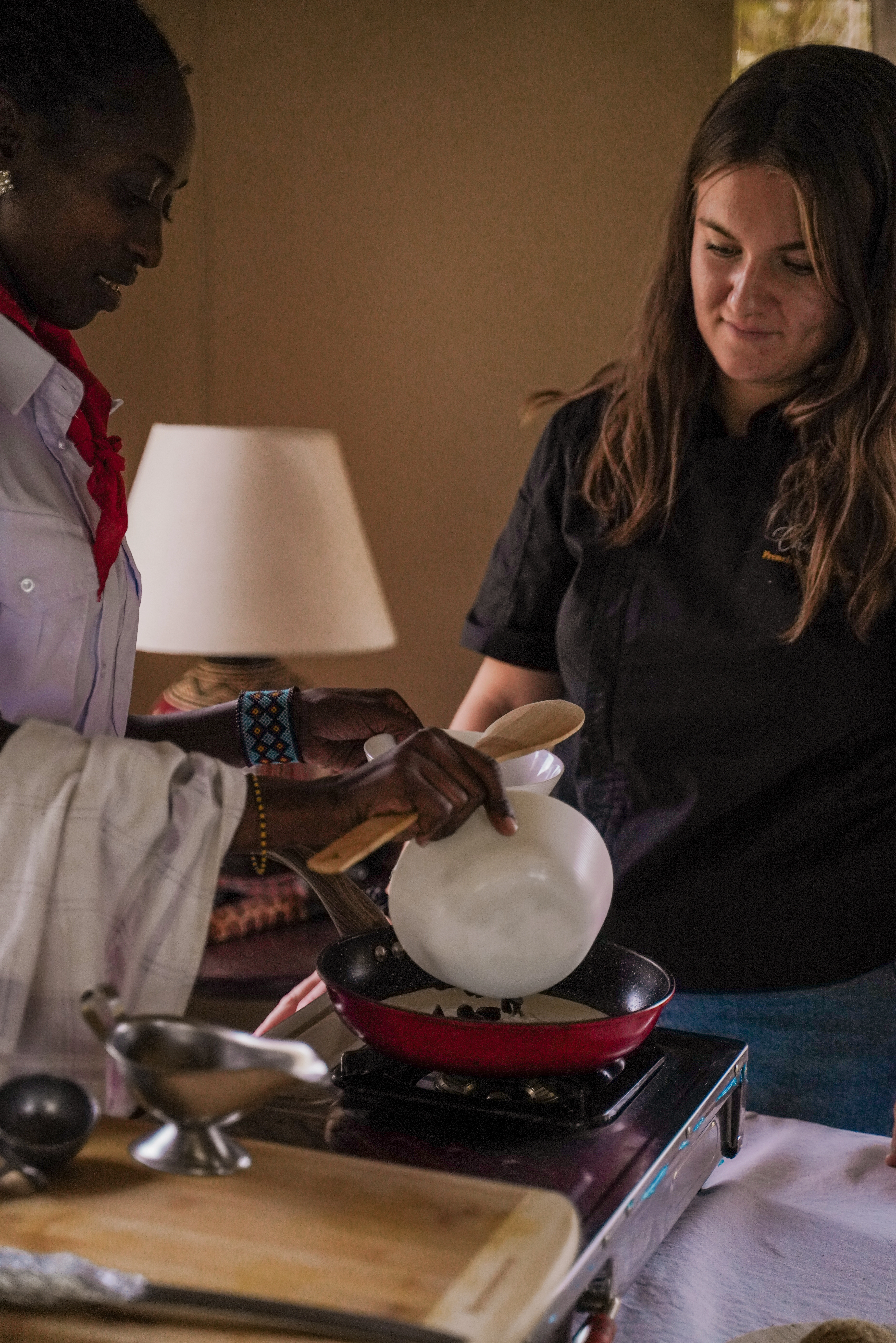 enkusero-kenya-training-coaching-stove On-site training — Charlotte coaching chef over portable stove in tented kitchen